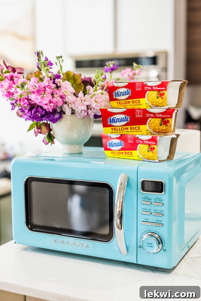 Minute Rice containers neatly stacked on top of a sleek blue microwave, emphasizing the product's convenience and readiness for quick meals.