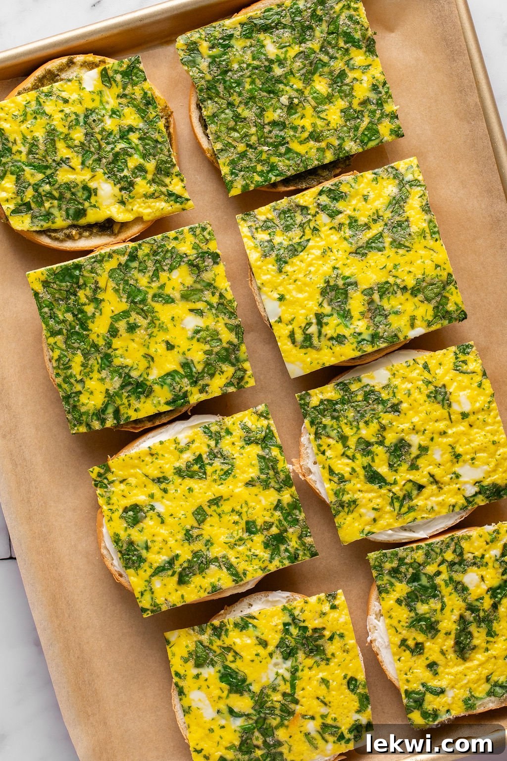 A parchment lined baking sheet with bags topped with sheet pan egg slices with spinach.