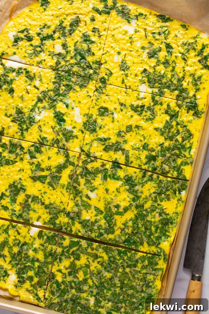Fully cooked and sliced sheet pan eggs on a baking sheet, ready for assembly into sandwiches.