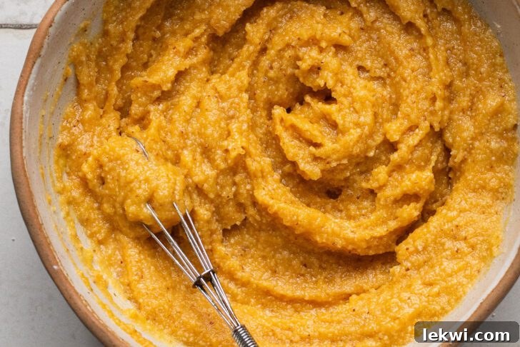 Close-up of corn dog mini muffin batter being whisked smoothly in a bowl, highlighting the texture and color.