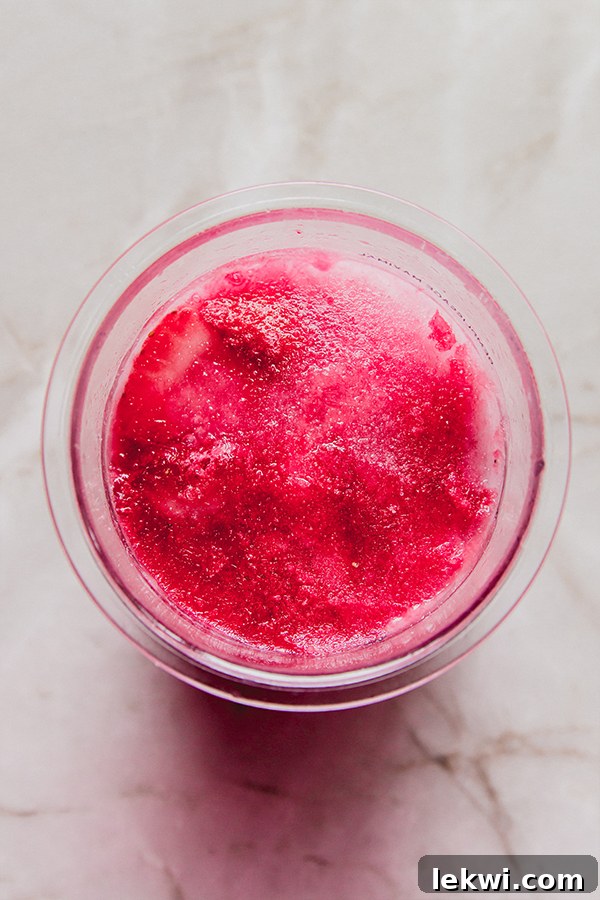 The Ninja Creami container with the strawberry pink drink sorbet mixture, fully frozen solid and ready for spinning.