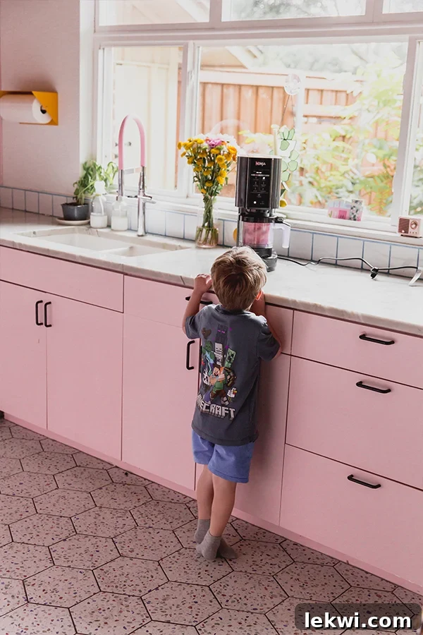 The Ninja Creami actively blending the strawberry pink drink sorbet mixture on a kitchen counter.