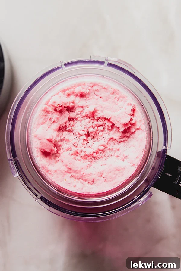 The strawberry pink drink sorbet mixture in the Ninja Creami container after its initial blend, showing a crumbly texture before respins.