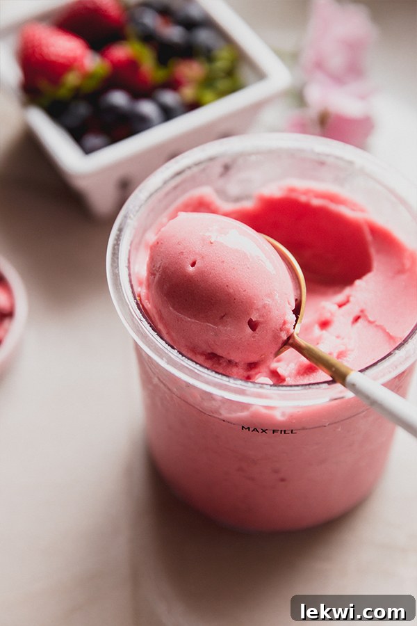 A close-up shot of the perfectly creamy and smooth Strawberry Pink Drink Sorbet in a glass dish, garnished with crushed freeze-dried strawberries.