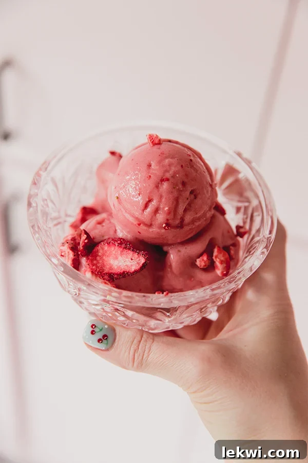 Strawberry pink drink sorbet scooped into a glass dish and topped with crushed freeze dried strawberries.