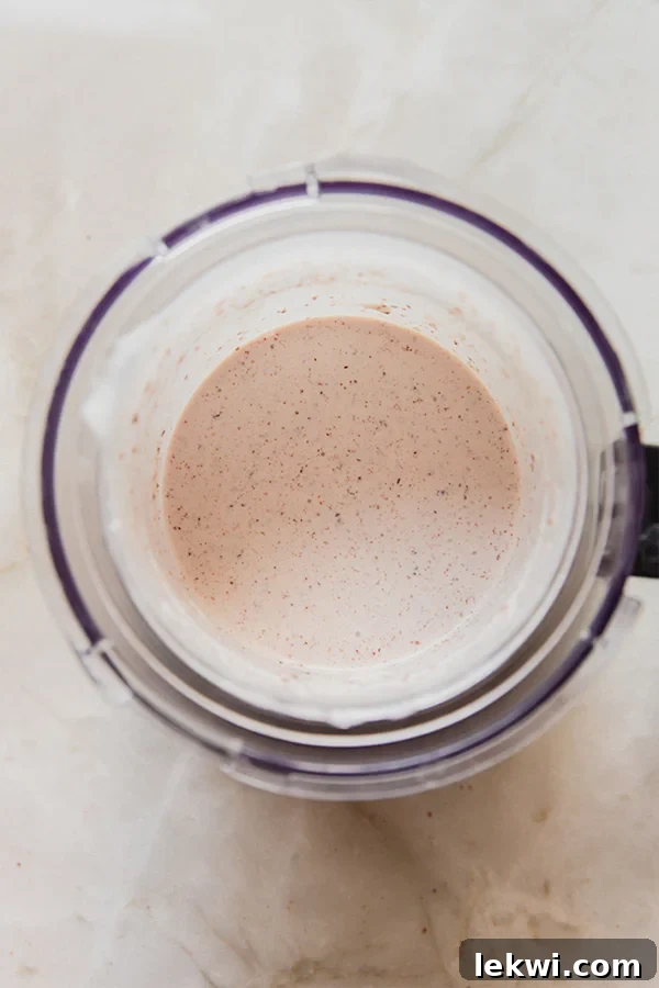 Almond milk, dairy-free ice cream, and gluten-free cookies fully blended into a creamy texture in a Ninja Creami cup.