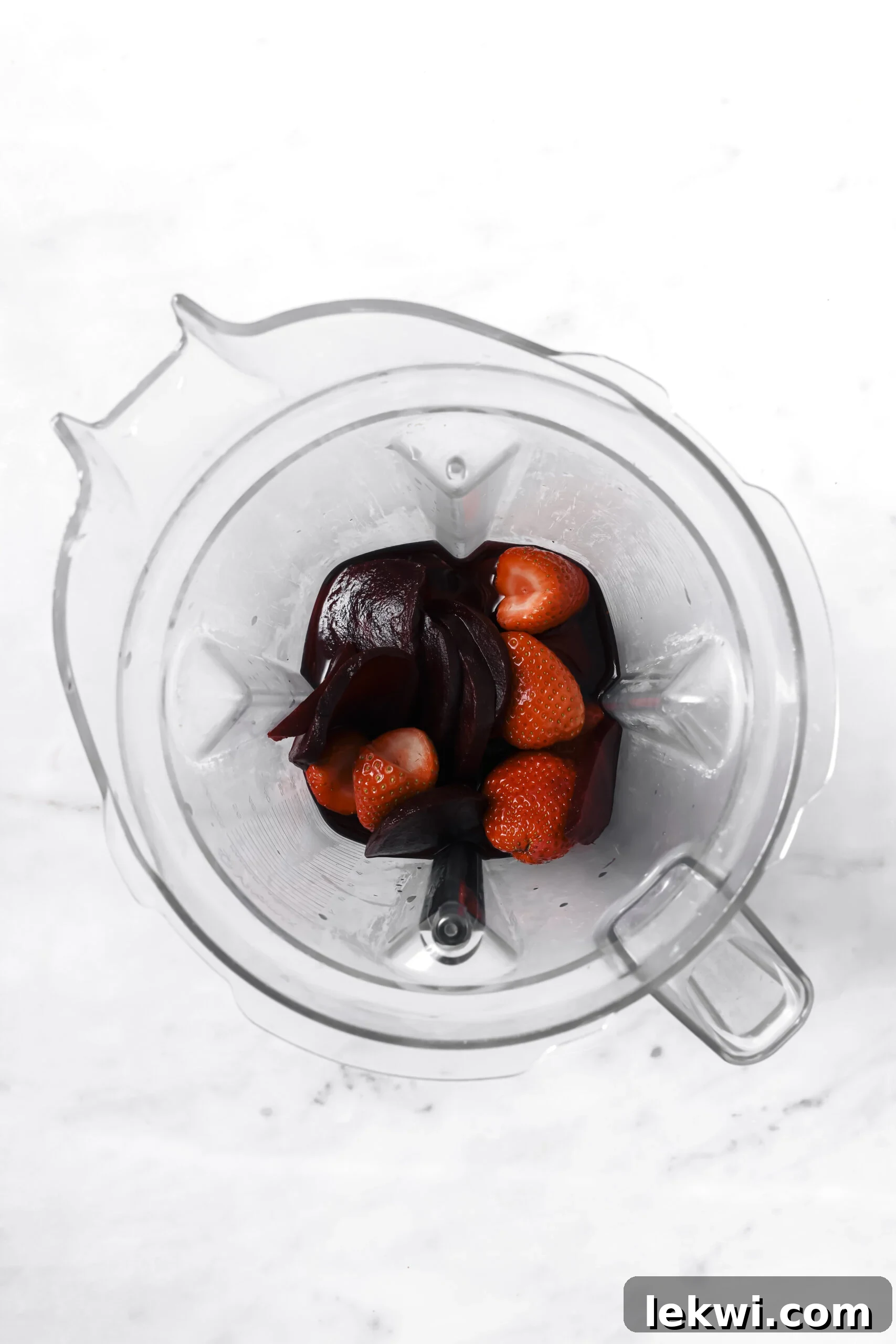 Fresh beets and strawberries in a blender, ready for blending into a healthy freezer pop mixture.