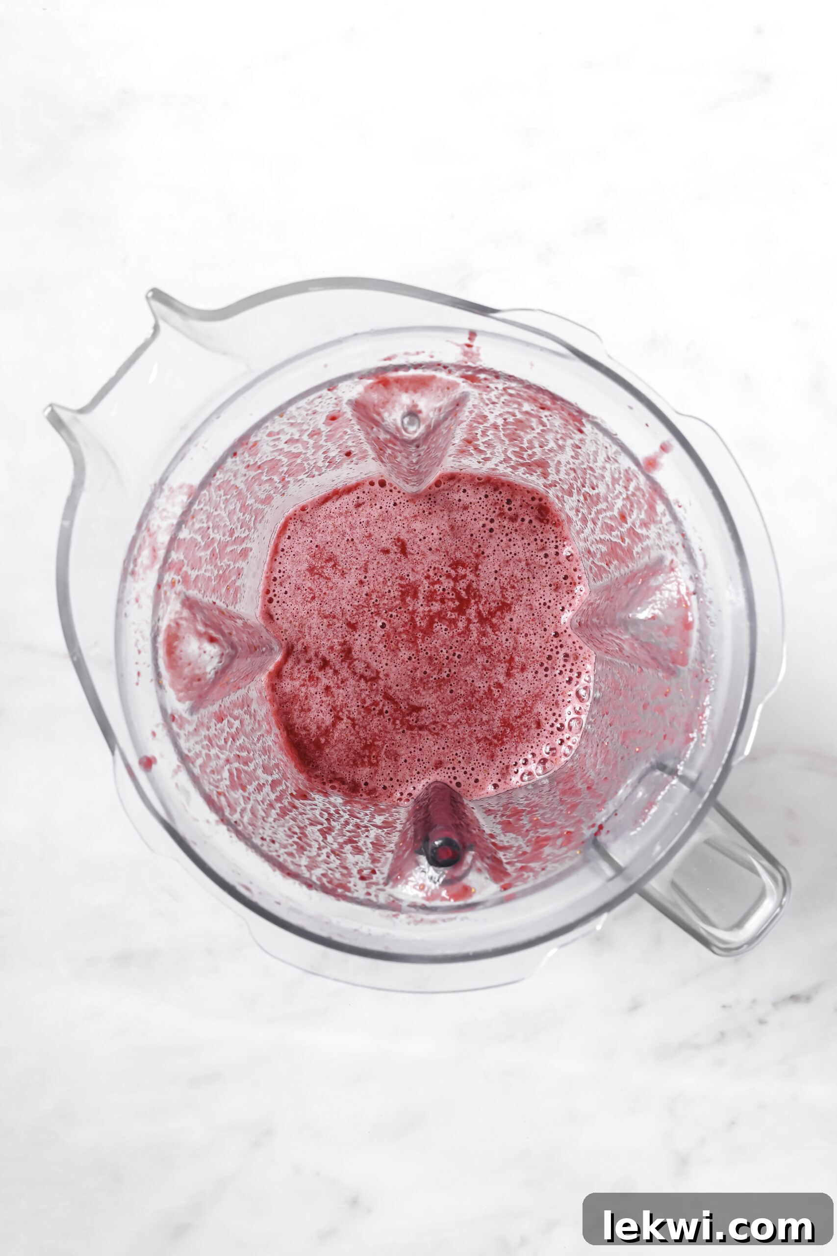 The strawberry and beet mixture fully blended into a smooth, vibrant liquid inside the blender.