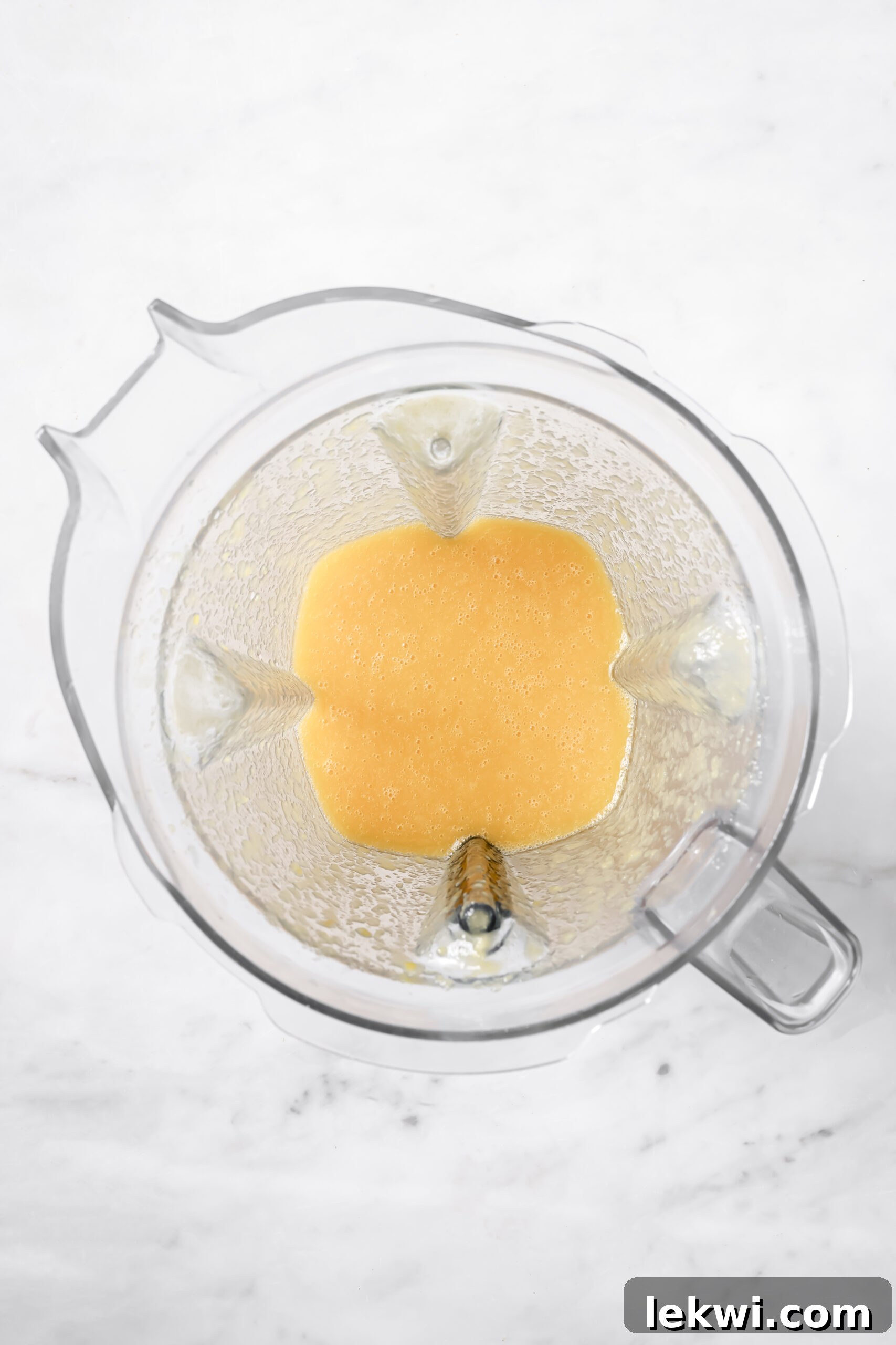The mango, peach, and orange juice mixture fully blended into a smooth, creamy liquid in the blender.