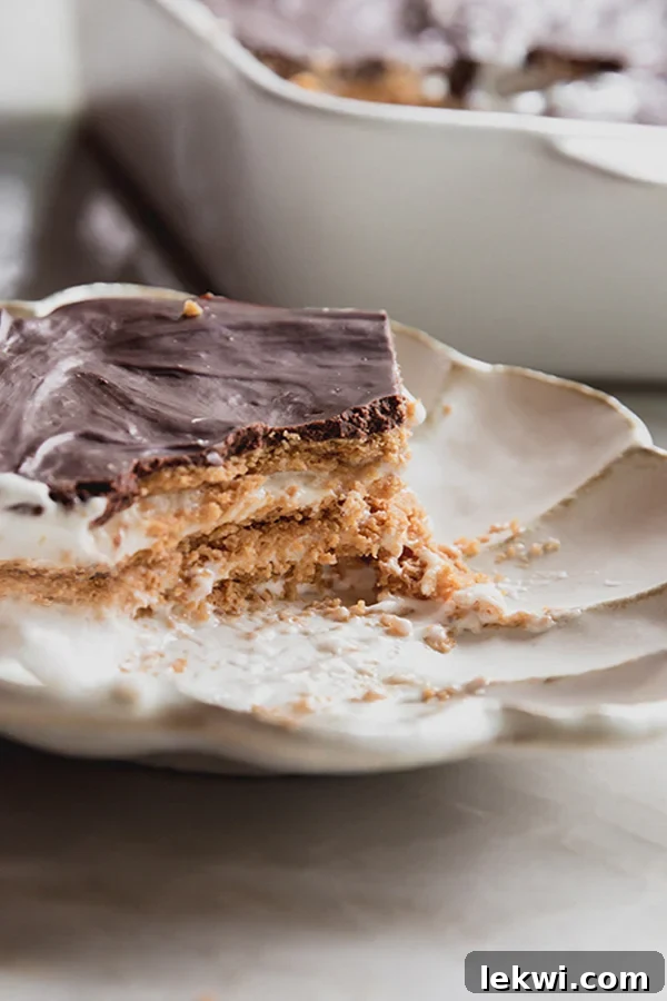 A perfectly sliced piece of gluten and dairy-free eclair cake on a plate, showing the distinct creamy and cracker layers, with the rich ganache on top.