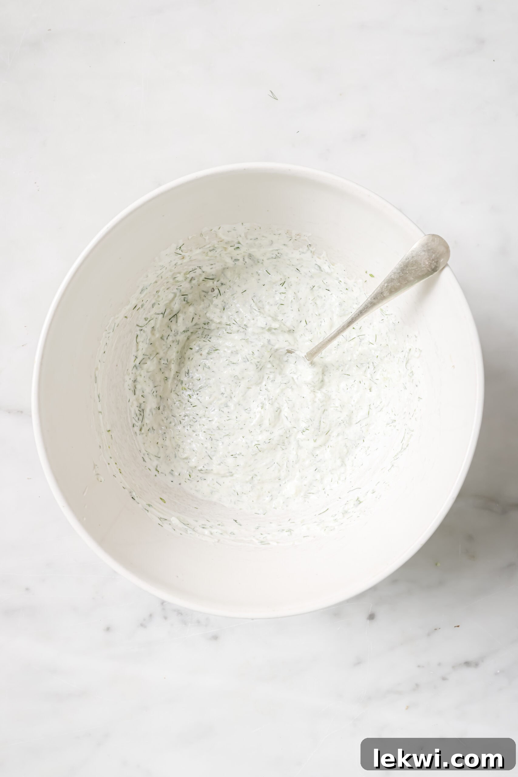 Dairy free tzatziki mixed in a bowl with a spoon.