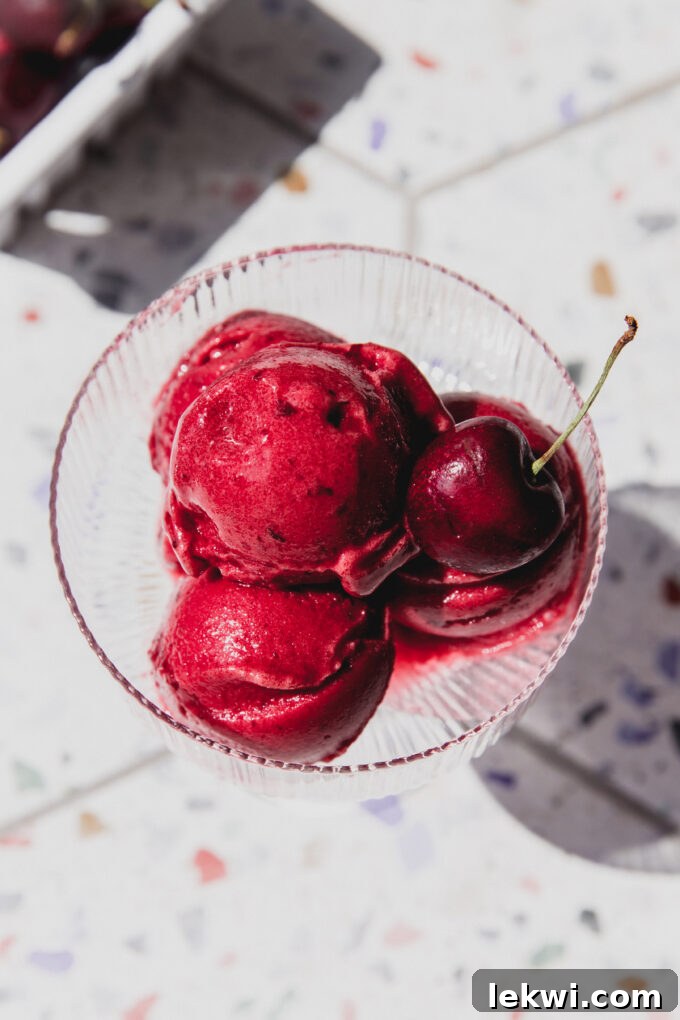Three scoops of shirley temple sorbet in a glass, topped off with a cherry.