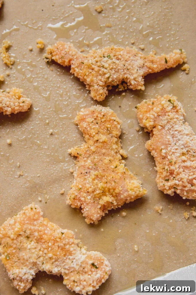 Raw dino-shaped nuggets on parchment paper.