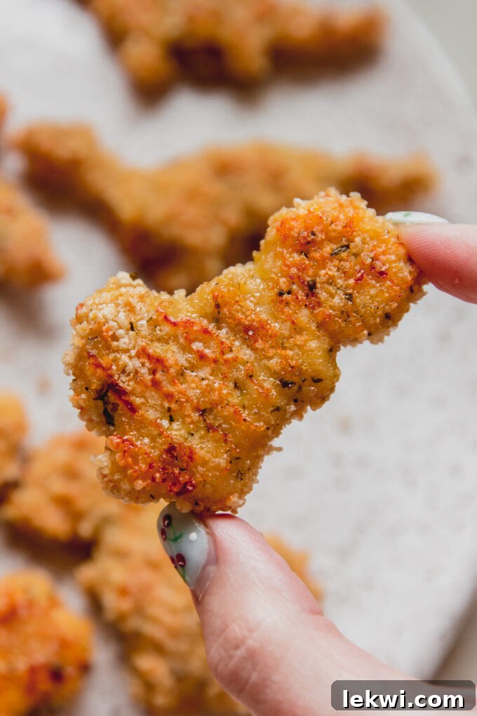 Person holding a gluten-free dino nugget.