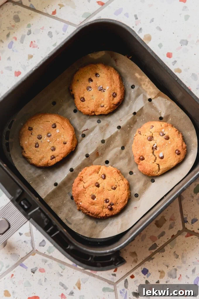 Air fryer chocolate chip cookies, fully cooked on parchment paper in the air fryer basket.