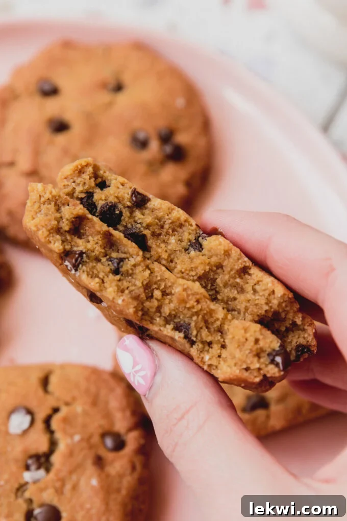 Air fryer chocolate chip cookie broken in half and being held.