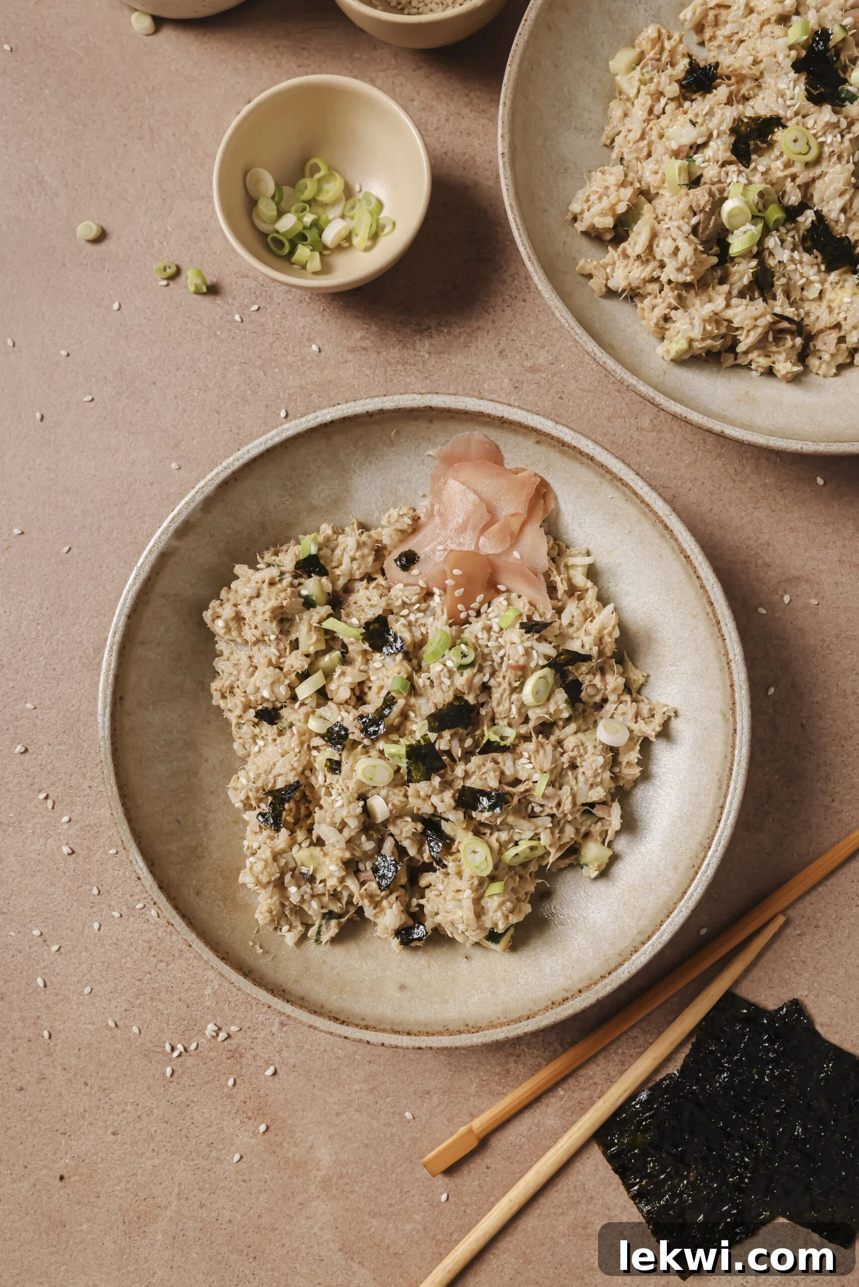 Avocado tuna rice bowl in a beige bowl and topped with pickled ginger on the side.