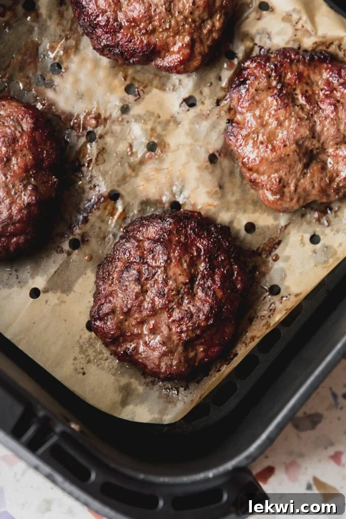 Air fryer burgers cooked in the air fryer with vented parchment paper. 