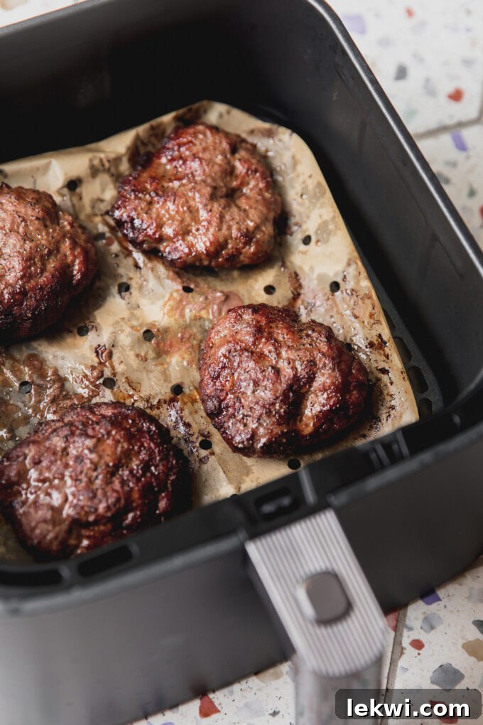 Air fryer burgers cooked in the air fryer with vented parchment paper.