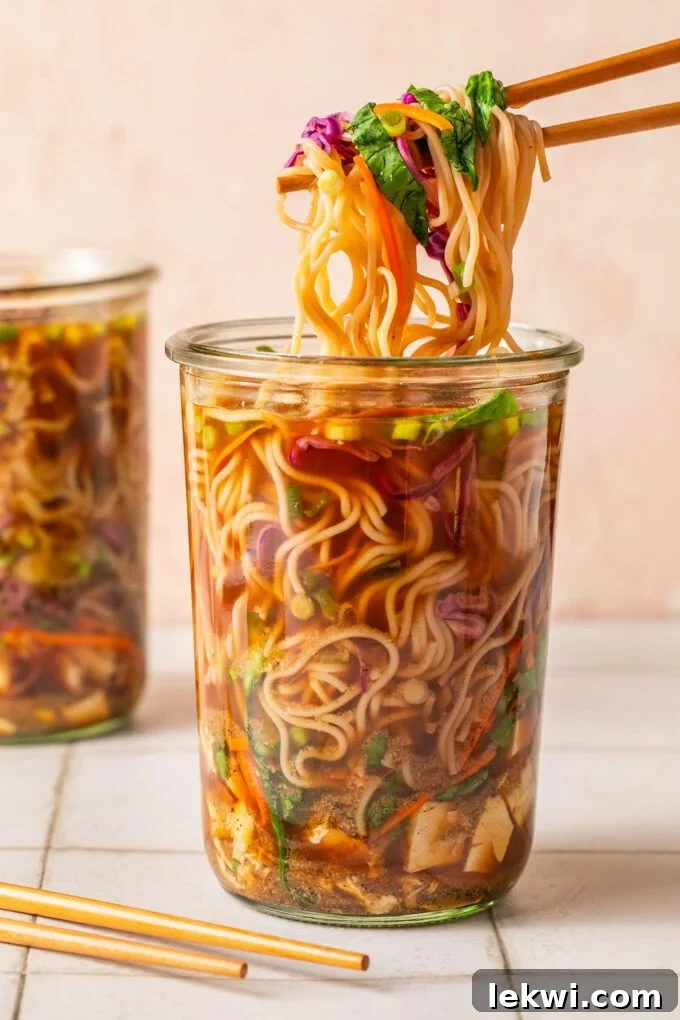 Two instant cup of noodles, one with chopsticks pulling up the ramen from a glass jar.
