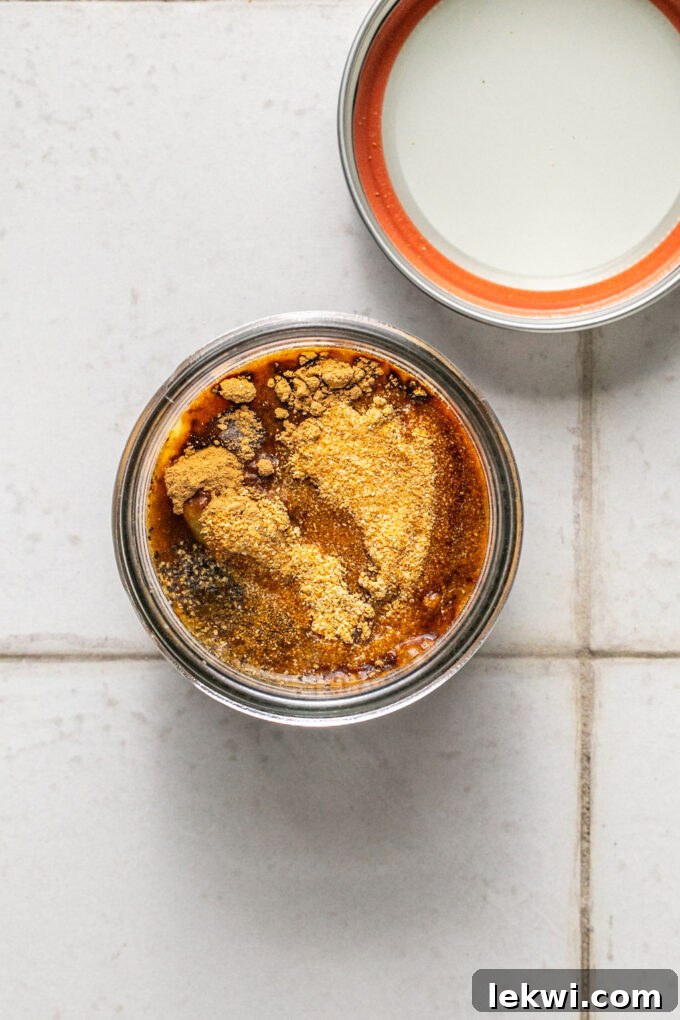 Small glass jar with chicken bouillon, seasonings, and coconut aminos, unmixed.