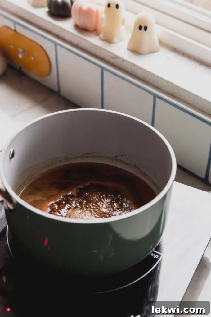 Pumpkin spice syrup gently simmering in a saucepan on the stove, steam rising.