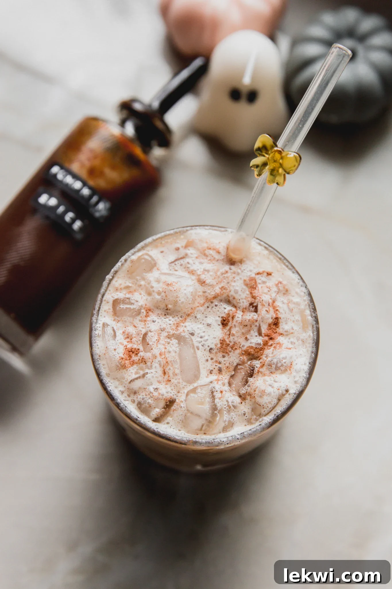 A beautiful pumpkin spice latte, garnished with cinnamon, with a bottle of homemade syrup sitting next to it.