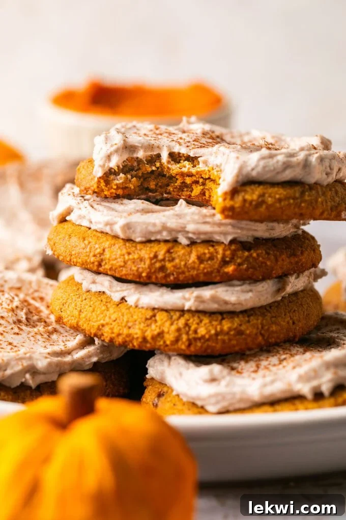 Three perfectly frosted gluten-free pumpkin spice latte cookies stacked elegantly on top of each other, showcasing their inviting texture and rich autumnal colors.