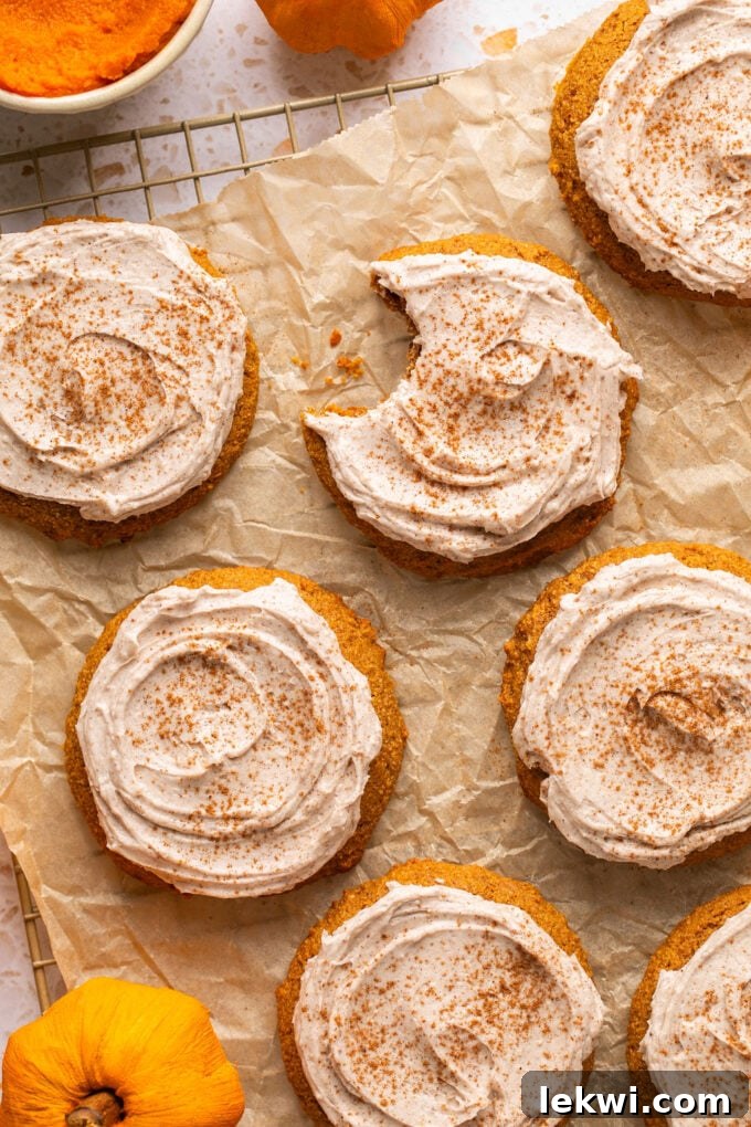 Delicious pumpkin cookies topped with creamy latte frosting, arranged neatly on a wire rack with parchment paper underneath.