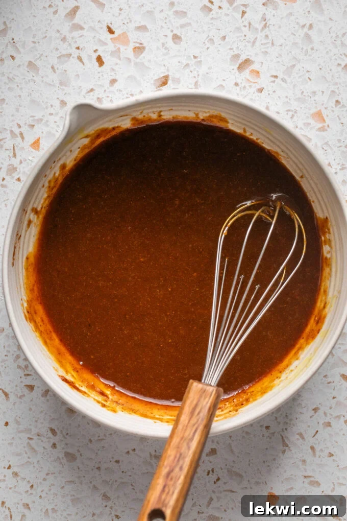 Pumpkin spice cookie wet ingredients, including pumpkin puree and melted coconut oil, whisked smoothly in a bowl.