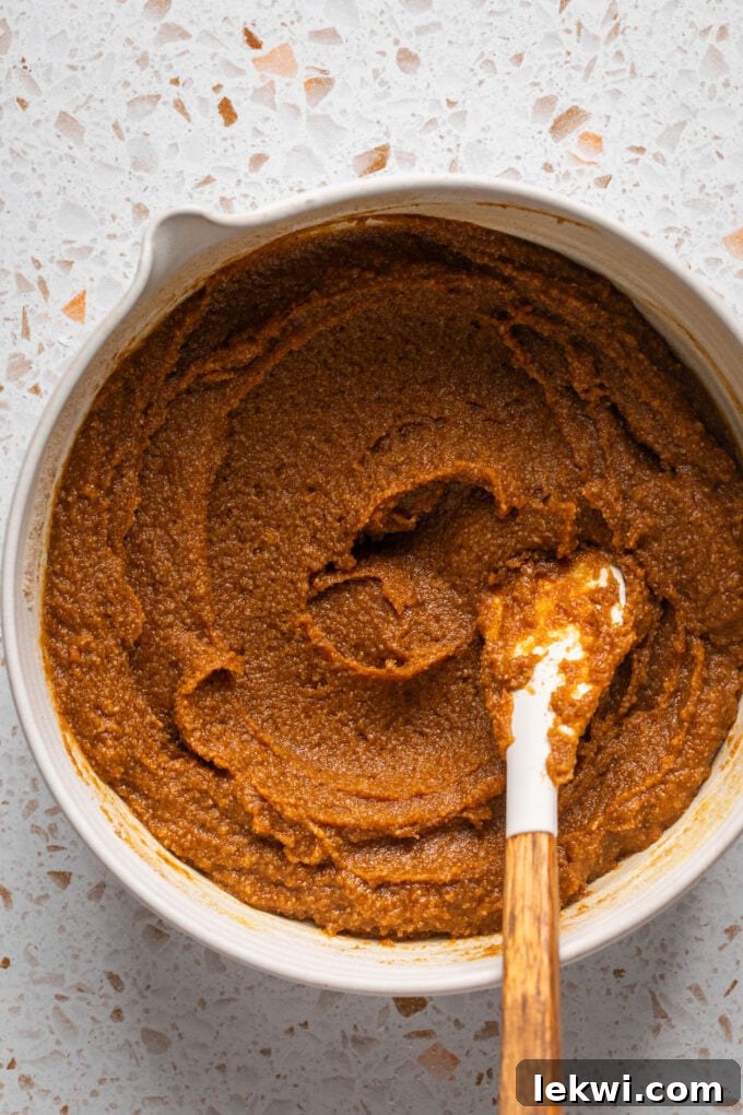 Soft pumpkin cookie batter resting in a bowl with a spoon, showing its creamy, ready-to-scoop texture.
