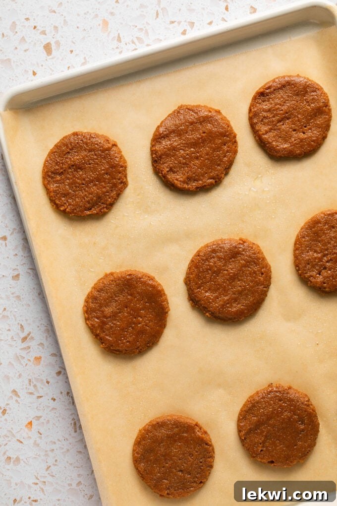 Unbaked gluten-free pumpkin cookie dough balls neatly arranged on a baking sheet, flattened and ready for the oven.