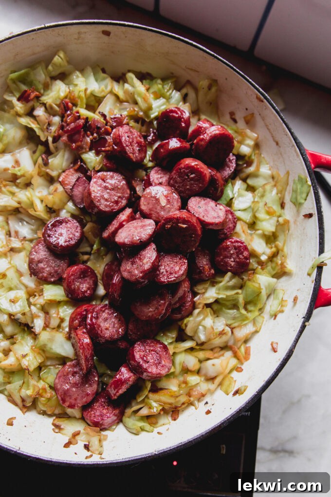 Sausage chopped and cooked in a pan with cooked cabbage.