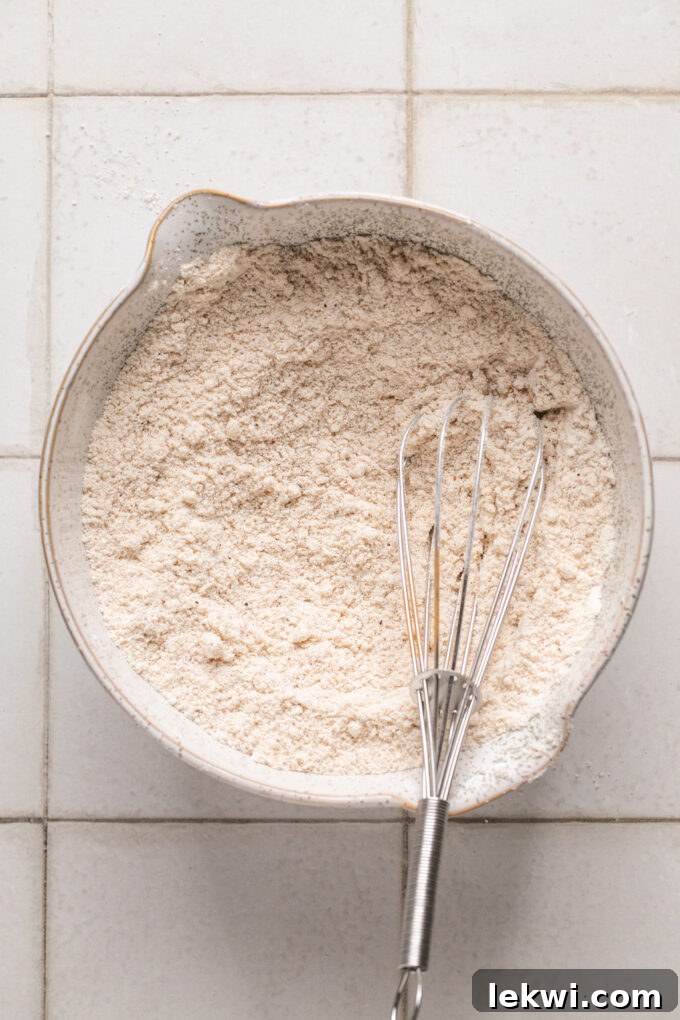 Dry ingredients for honey apple cake being whisked together in a white bowl.