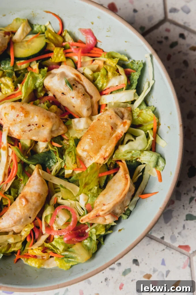 A generous serving of potsticker salad in a large, inviting blue bowl, showcasing the colorful ingredients and crispy potstickers.