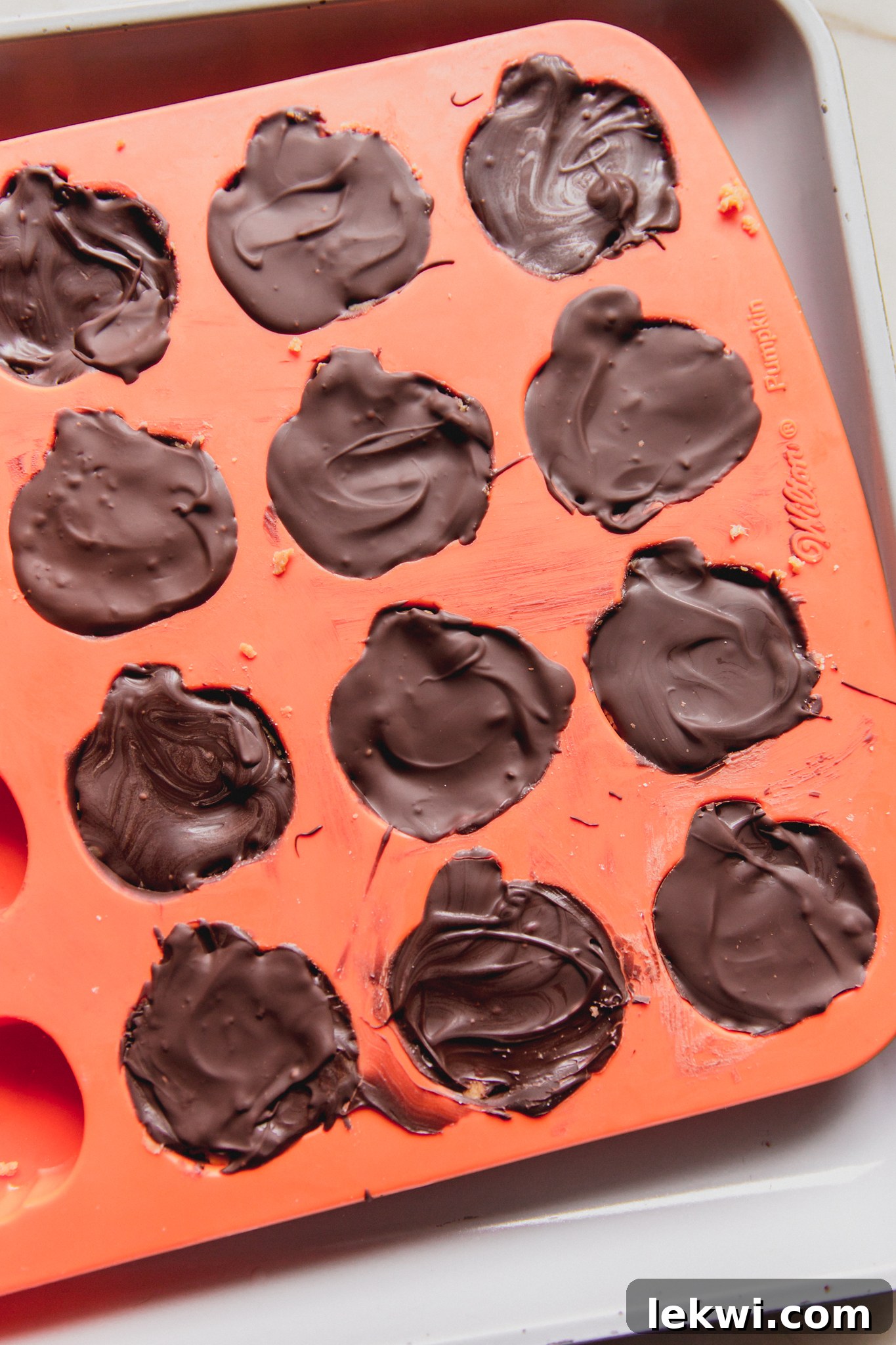 Mini almond butter Reese's cups in a pumpkin mold, ready to be chilled.