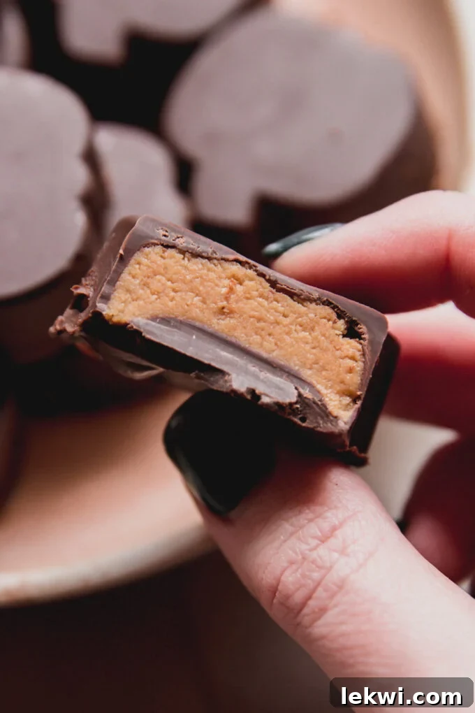 Almond butter cups with a bite taken and being held, showcasing the rich filling and chocolate coating.