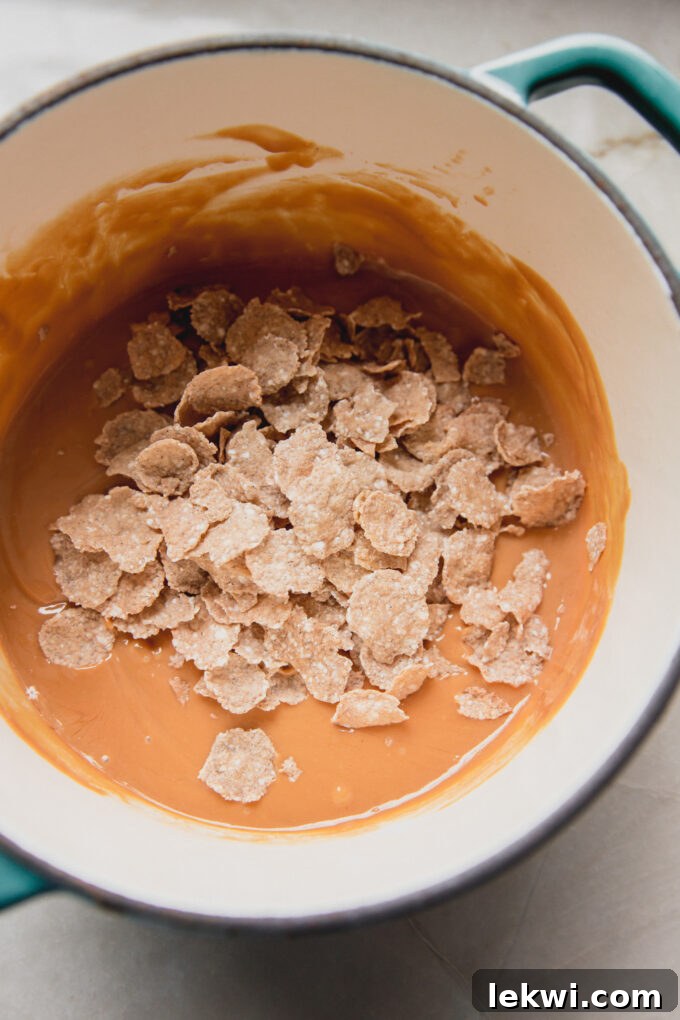 Melted nut butter with flake cereal, unmixed, in a pot.