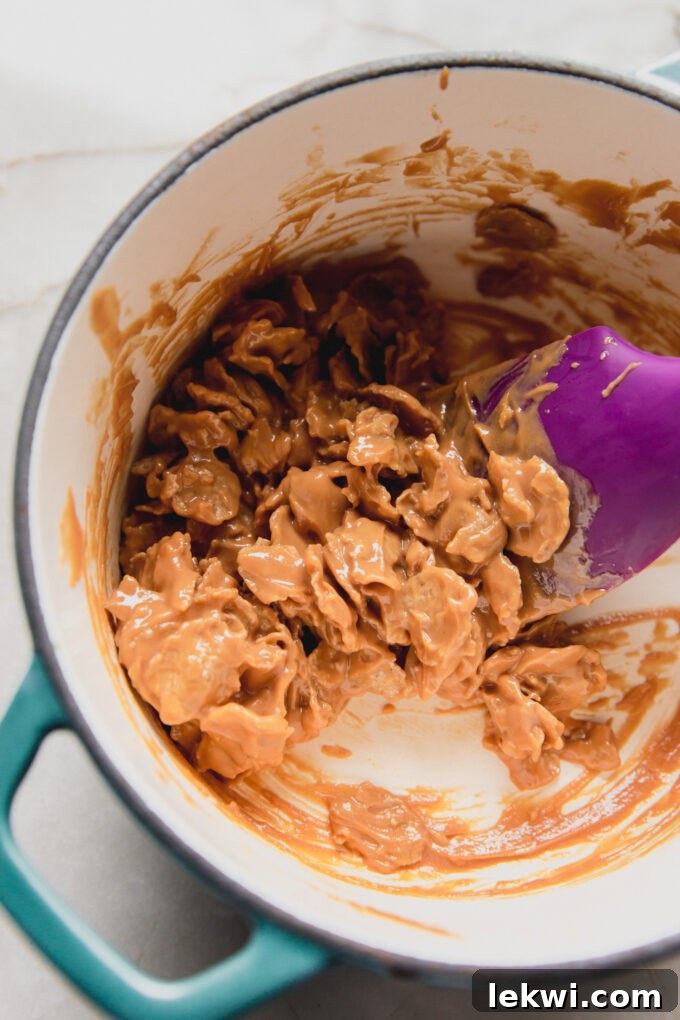 Melted nut butter with flake cereal, mixed, in a pot.