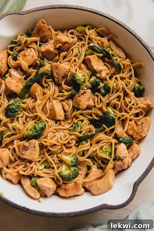 A perfectly cooked chicken and broccoli ramen stir fry resting in a pristine white pan, ready to be served.