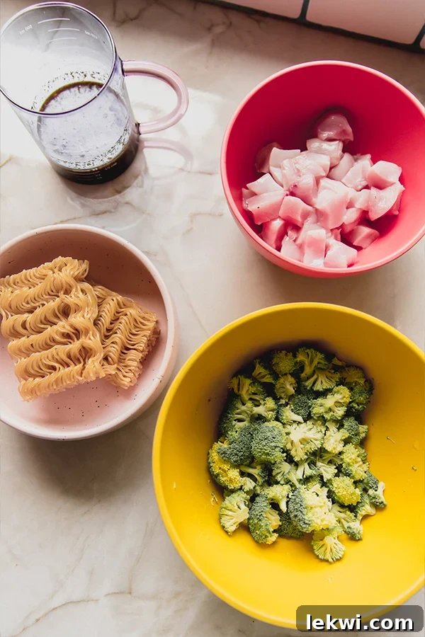 A colorful array of chicken and broccoli ramen ingredients meticulously arranged in small white bowls, ready for cooking.