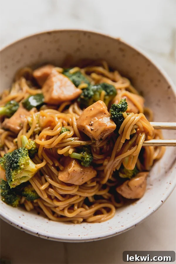 Two bowls of chicken and broccoli ramen, perfectly plated and garnished, with chopsticks resting beside them.