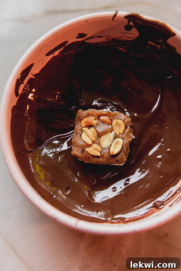 Mini Snickers bars topped with peanuts, ready to be dipped in melted chocolate.