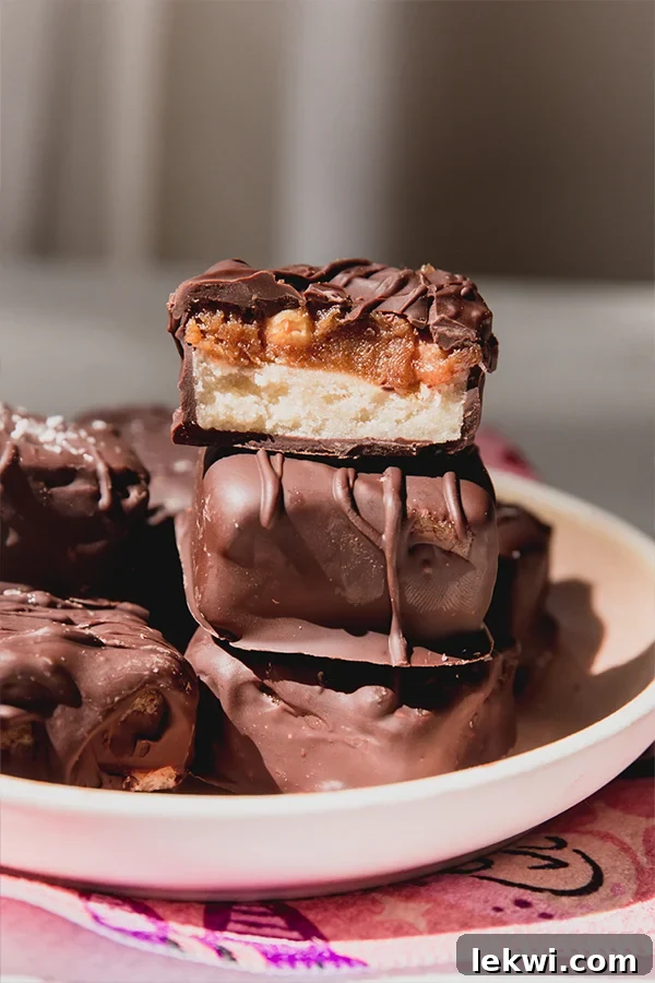 Three mini healthier Snickers bars, one cut in half revealing the delicious multi-layered filling.