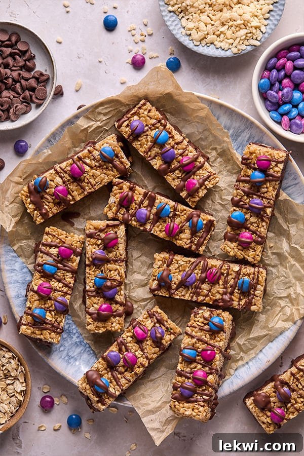 Vibrantly decorated Kudos bars, topped with colorful candy gems and a luscious chocolate drizzle, artfully arranged on a serving platter.