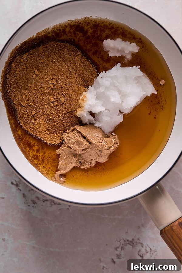 Coconut sugar, coconut oil, and nut butter warming in a pot, beginning to melt and combine.