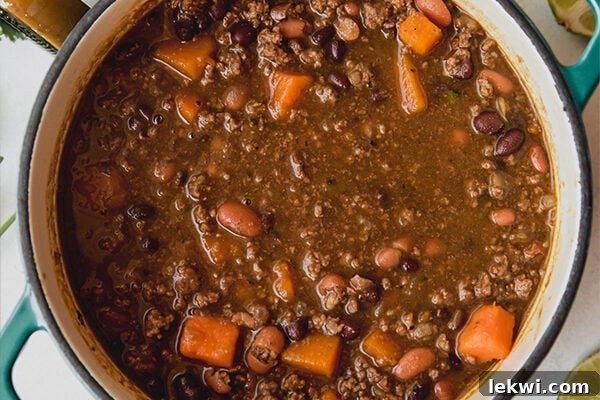 A large pot filled with rich, simmering nightshade-free chili, showcasing its thick, hearty texture and the vibrant mix of vegetables and ground beef, nearly ready to serve.