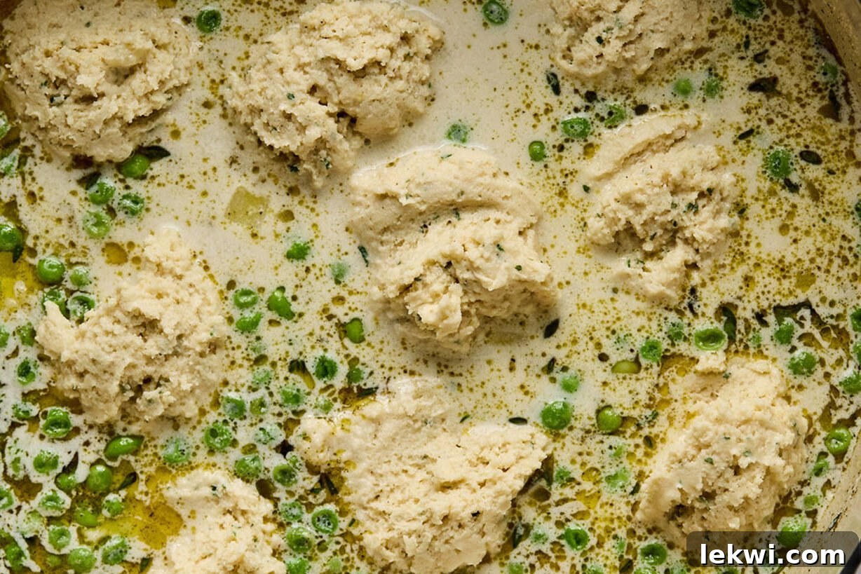 Gluten-free dumpling dough scooped onto the simmering soup broth before cooking.