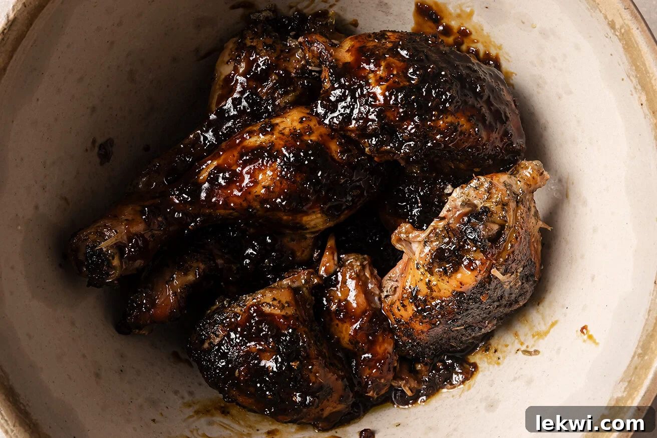 Cooked turkey wings being tossed in a bowl with a rich, glossy orange glaze.
