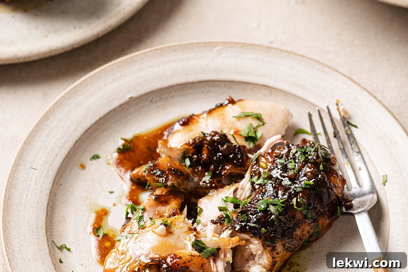 A perfectly glazed turkey wing presented on a plate, garnished with fresh thyme.
